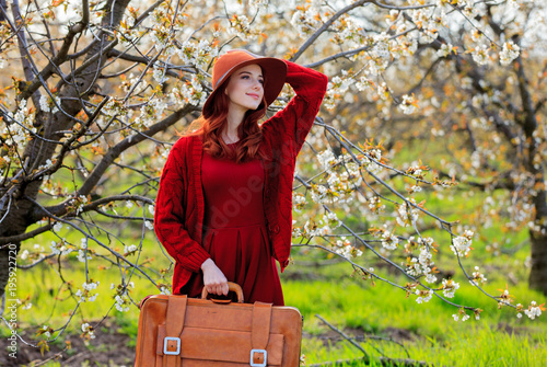 girl with suitcase in blossom cherry garden