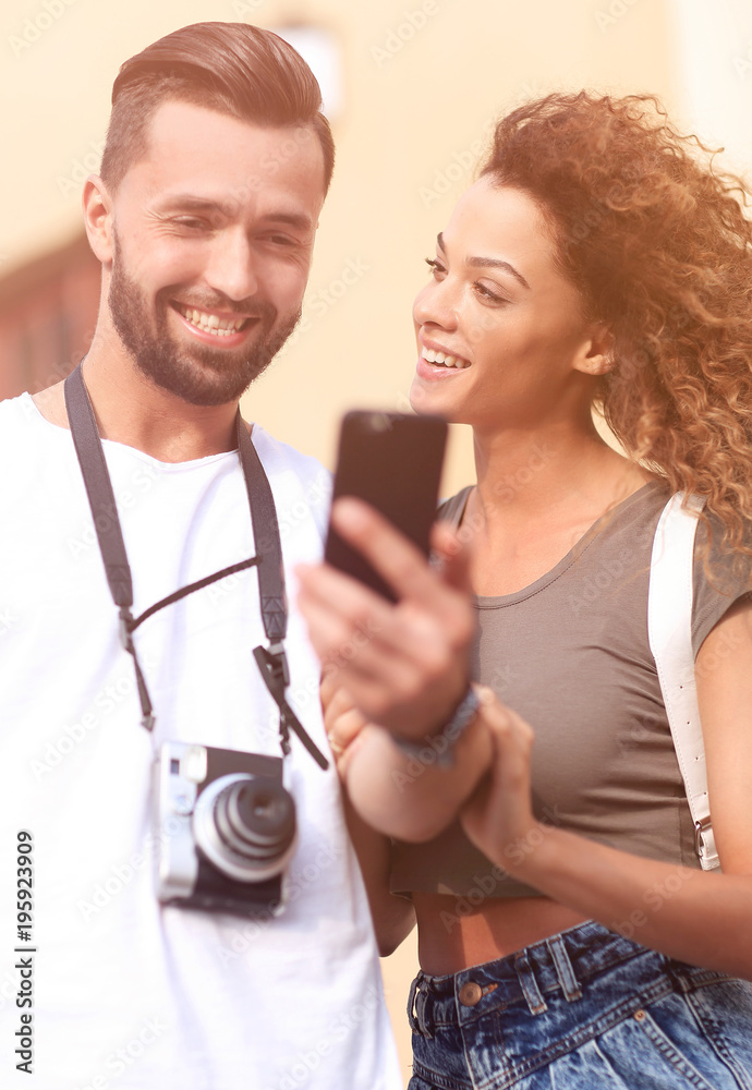 Happy young couple searching for location both on mobile phone Happy young couple searching for location both on mobile phone