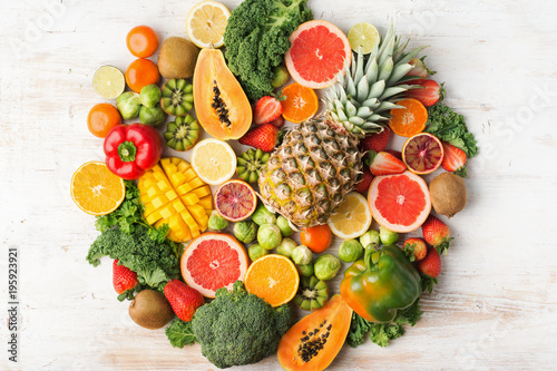 Fruits and vegetables rich in vitamin C background circle shape  oranges mango grapefruit kiwi kale pepper pineapple lemon sprouts papaya broccoli  on white table  top view  selective focus