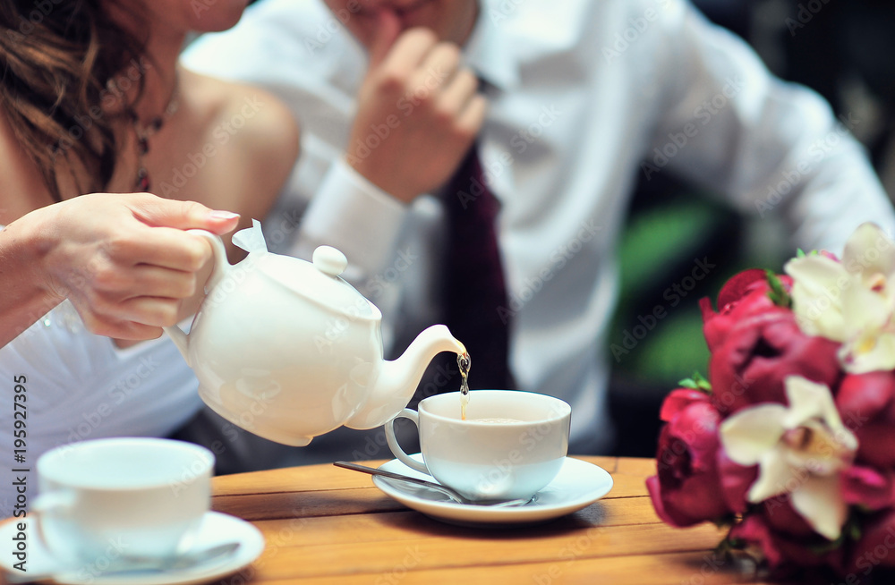 A newlywed couple drinking hot coffee or tea with sweet dessert in warm cozy cafe with wedding bouquet on the table. Atmoshere of happiness of new family and love tenderness A newlywed couple drinking hot coffee or tea with sweet dessert in warm cozy cafe with wedding bouquet on the table. Atmoshere of happiness of new family and love tenderness