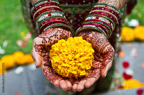 Closeup of Henna tattooed hands holding beautiful yellow flower photo