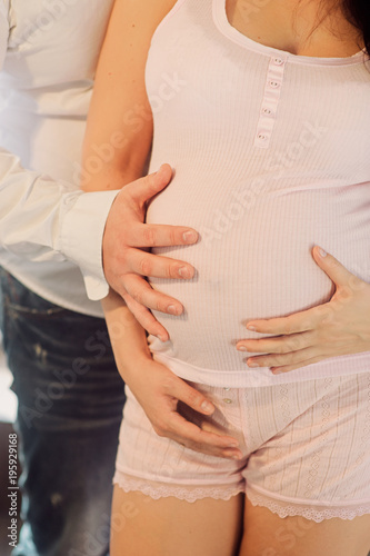 Wallpaper Mural Pregnant woman in dress with her man holds hands on belly on a white background. Pregnancy, maternity, preparation and expectation concept. Close-up indoors. Beautiful tender mood photo of pregnancy. Torontodigital.ca