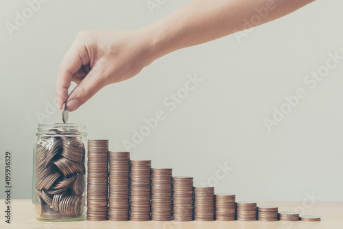 Hand putting coins in jar with money stack step growing growth, Saving money or investment financial plan with efficiency and quality to increase sustainable growth and stability in the future photo