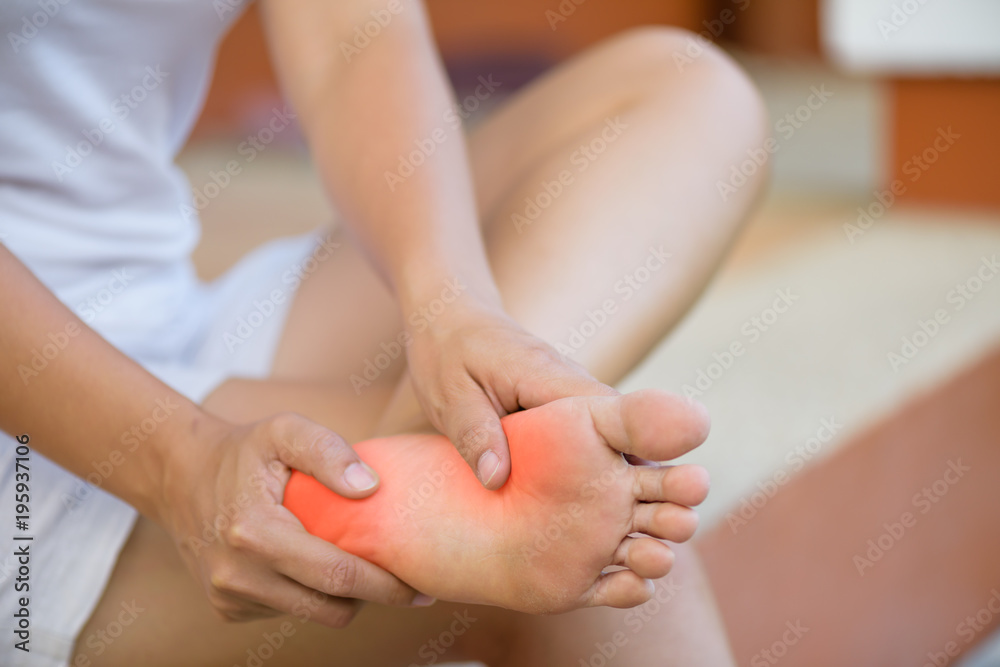 Closeup young woman feeling pain in her foot at home. Healthcare and medical concept. Closeup young woman feeling pain in her foot at home. Healthcare and medical concept.