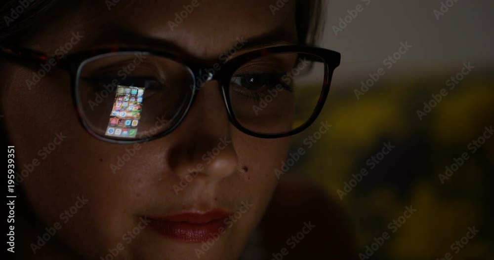 4K Close up girl using smartphone in the dark with interface reflected in her glasses