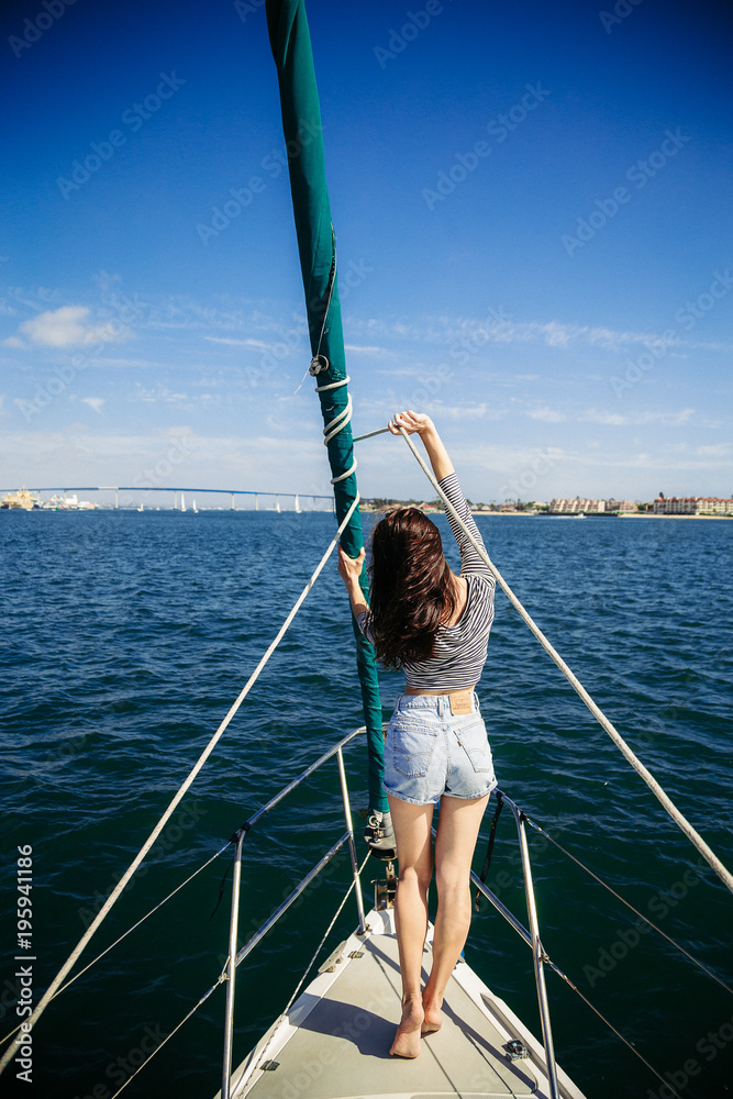 Brunette young girl, woman on sailboat, boat in striped jacket at summer time. California, San Diego