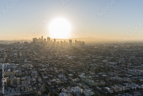 Aerial view of sunrise behind streets and buildings in the urban core of Los Angeles California.
