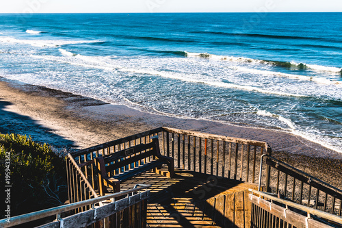 A bench rests on a landing for the stairway access to the beach at South Carlsbad State Beach in San Diego, California.