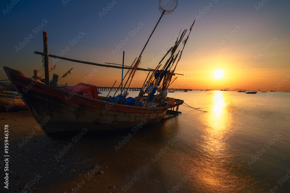 Fishing boat in on the beach at sunset.
