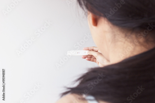 Selective focus happy couple hugging with positive pregnancy test in bedroom