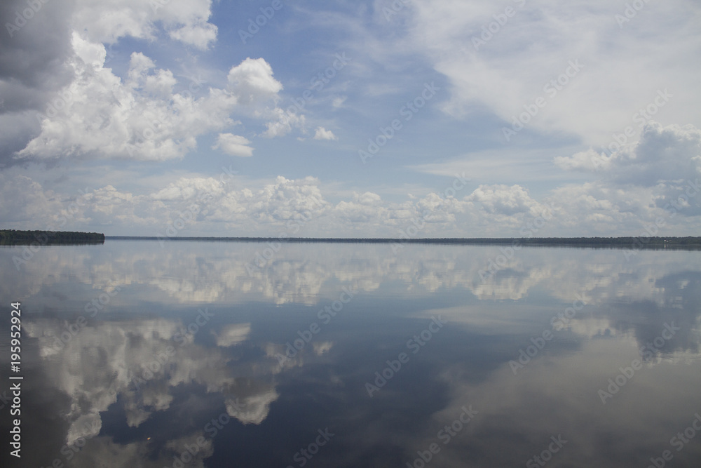 Travelling through Amazon by boat. Blue sky with clouds reflected on the 'Rio Negro' river. Amazon / Brazil