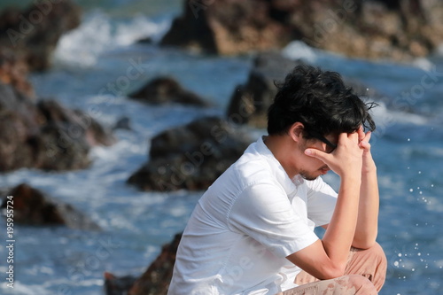 Anxious upset young Asian man covering face with hands at sea coast © tuaindeed