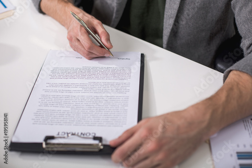 Great deal. Close up of male hands underwriting documents with pen photo