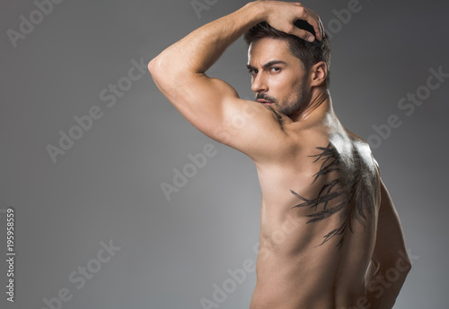 Fotografie Severe man with athletic torso standing with his back