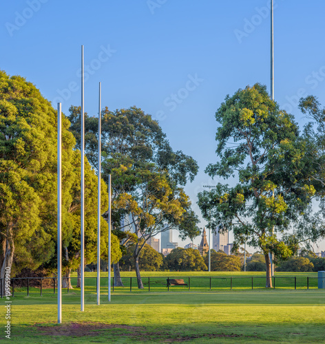 Four Australian football goal posts at a football oval in Carlton, with the city buildings of Melbourne, Australia in the background photo