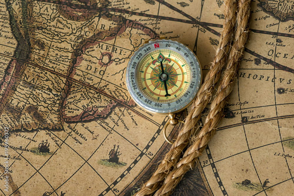 Old compass on vintage map with rope