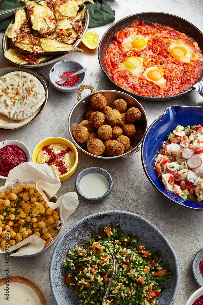 Overhead image of traditional jewish and middle eastern food: falafel, fattoush, tabouli, shakshuka, balila, hummus, roasted eggplants and spicy beetroot dip. Israeli cuisine concept Overhead image of traditional jewish and middle eastern food: falafel, fattoush, tabouli, shakshuka, balila, hummus, roasted eggplants and spicy beetroot dip. Israeli cuisine concept