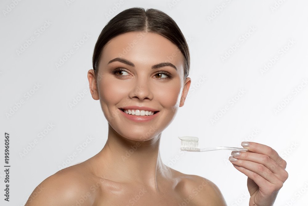 Brilliant smile. Portrait of happy young woman holding toothbrush with paste on it and laughing. Isolated Brilliant smile. Portrait of happy young woman holding toothbrush with paste on it and laughing. Isolated
