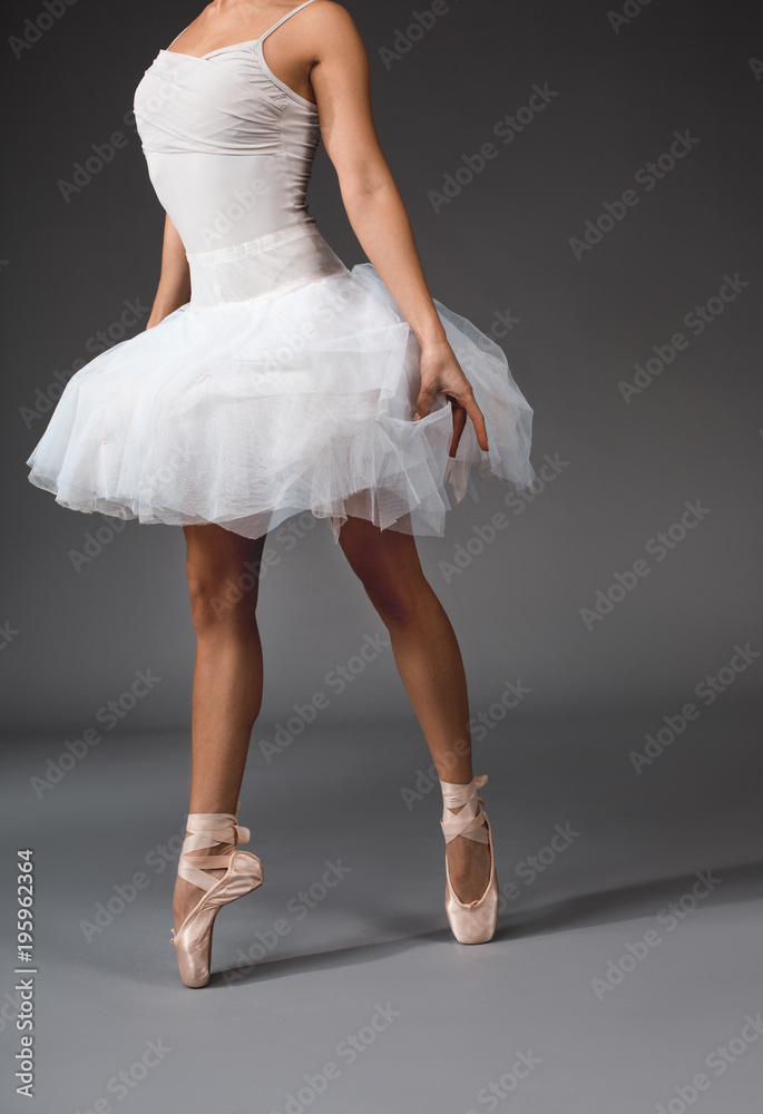 Airiness concept. Female body in tutu and satin slippers walking at the tips of her toes Airiness concept. Female body in tutu and satin slippers walking at the tips of her toes
