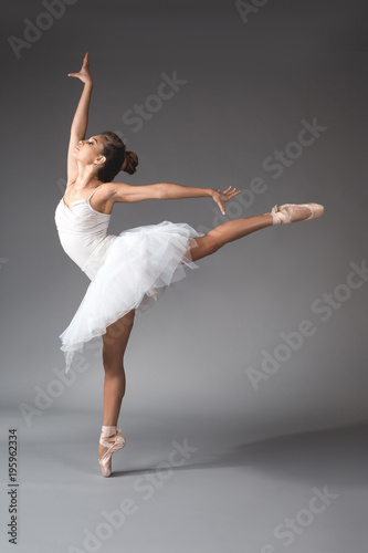 Fototapeta Naklejka Na Ścianę i Meble -  Ballet art concept. Full length of young woman wearing short dance skirt standing on tiptoes of one foot with gracefulness