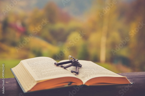Vintage keys on a open book with colorful autumn background