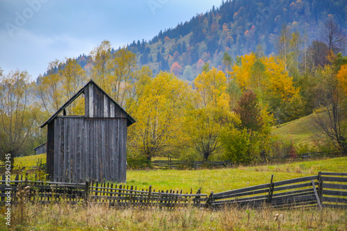 Autumn scenery landscape with colorful forest, wood fence and hay barns in Prisaca Dornei, Suceava County, Bucovina, Romania photo