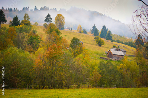 Autumn scenery landscape with colorful forest, wood fence and hay barns in Prisaca Dornei, Suceava County, Bucovina, Romania photo