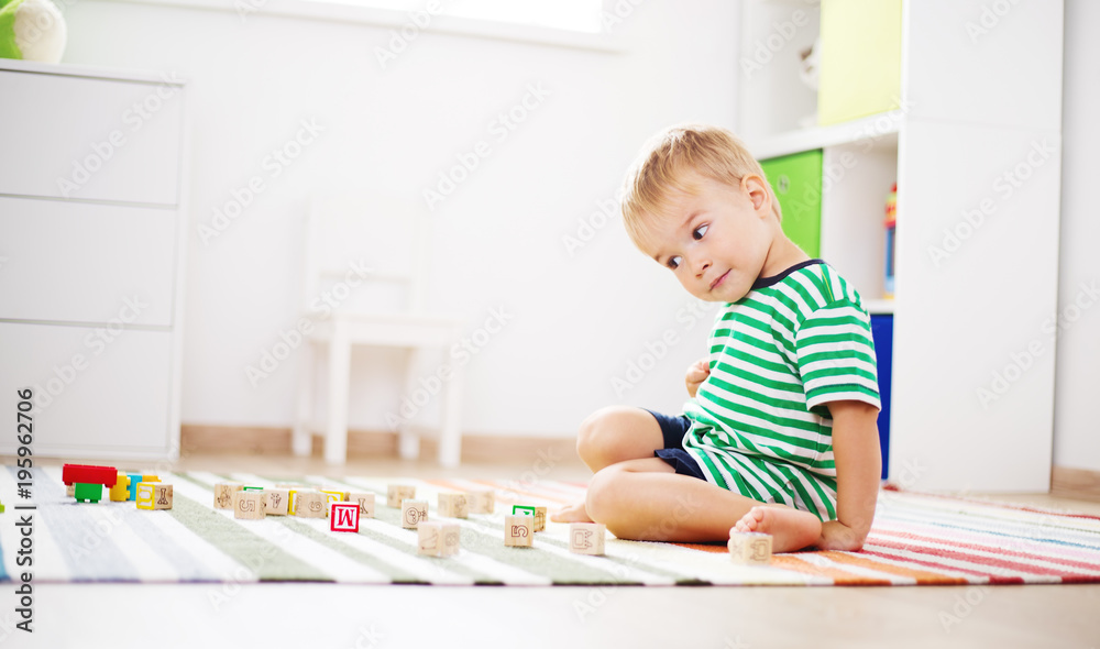 two years old child sitting on the floor with wooden cubes two years old child sitting on the floor with wooden cubes
