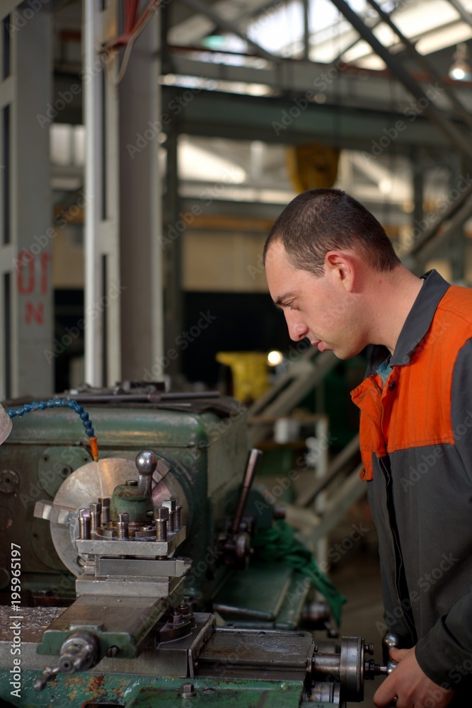 metalworking industry: factory man worker in uniform working on lathe machine in workshop metalworking industry: factory man worker in uniform working on lathe machine in workshop