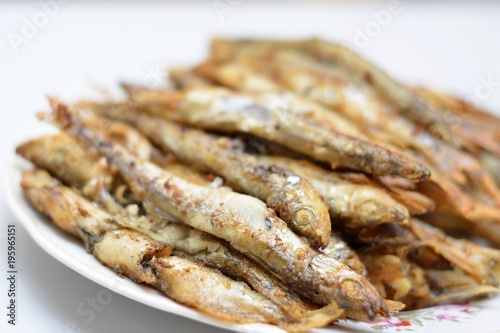Fried smelt in a frying pan on the table with spices, lime and thyme. Small crispy fish. Selective focus