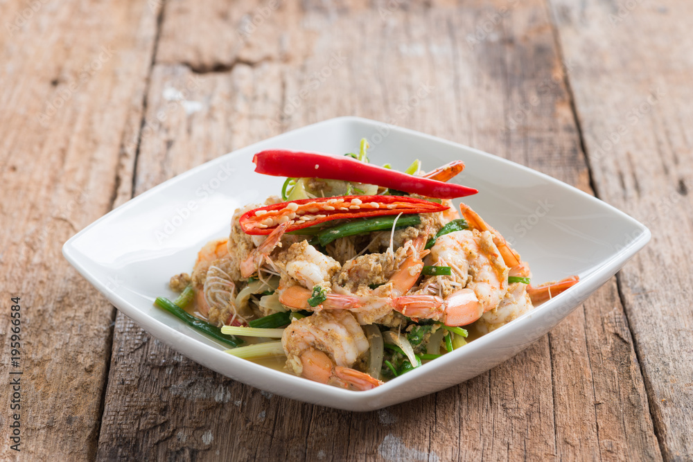 Stir-Fried Shrimp with Curry Powder in white plate on brown wood background Stir-Fried Shrimp with Curry Powder in white plate on brown wood background