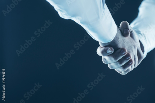 concept of a reliable partnership: a close-up of handshake of business partners on a black background.