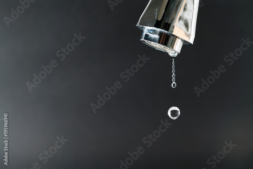 water drop on faucet with  black backgrounds, world water day concept with copy space