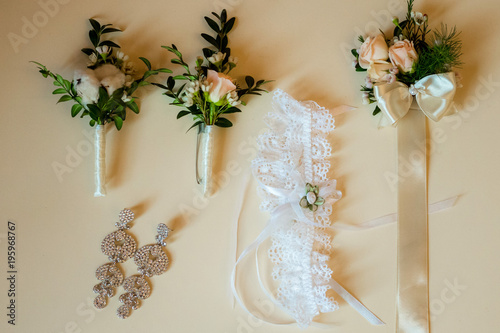 Flatlayout of wedding earrings, garter and boutonniere.top view photo