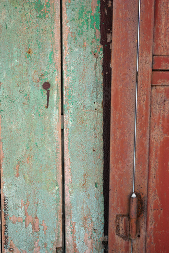 Door frame with shabby green and door with handle of dark red color, grunge texture background