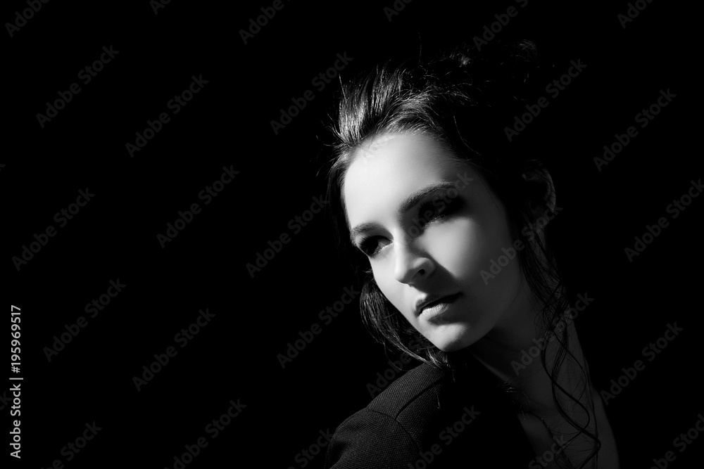 Girl in fashion style looks inside a close-up on a black background with space for text