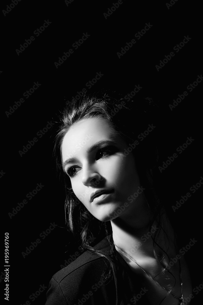 Girl in fashion style with professional make-up close-up on a black background in a low key