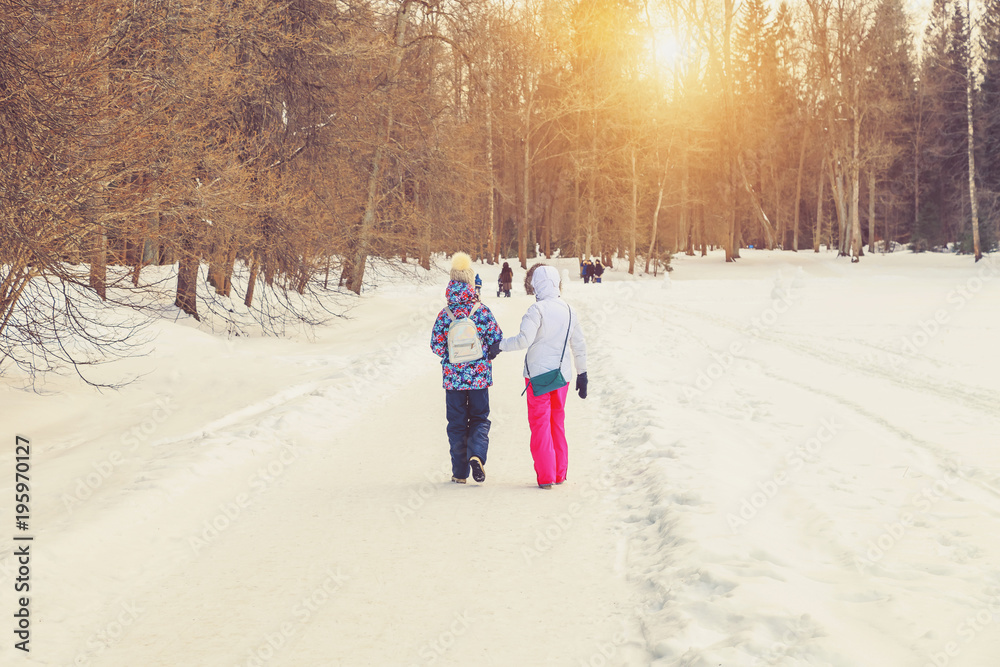 Mom and daughter in the park in the winter at sunset in Russia Mom and daughter in the park in the winter at sunset in Russia