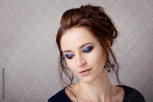 Brunette girl with professional make-up and stylish hair look down on a gray background
