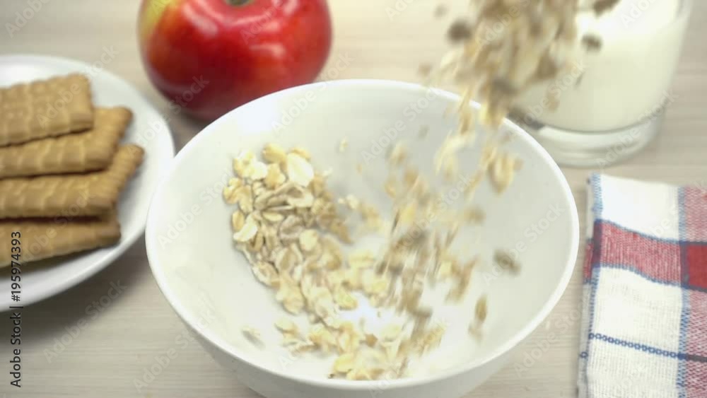 Oat flakes falling into white bowl in slow motion. Oat flakes falling into white bowl in slow motion.