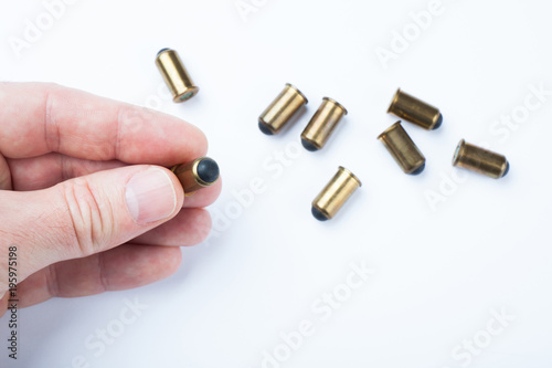 A bullet in a man's hand is a component of a firearm and is a shell. White background.