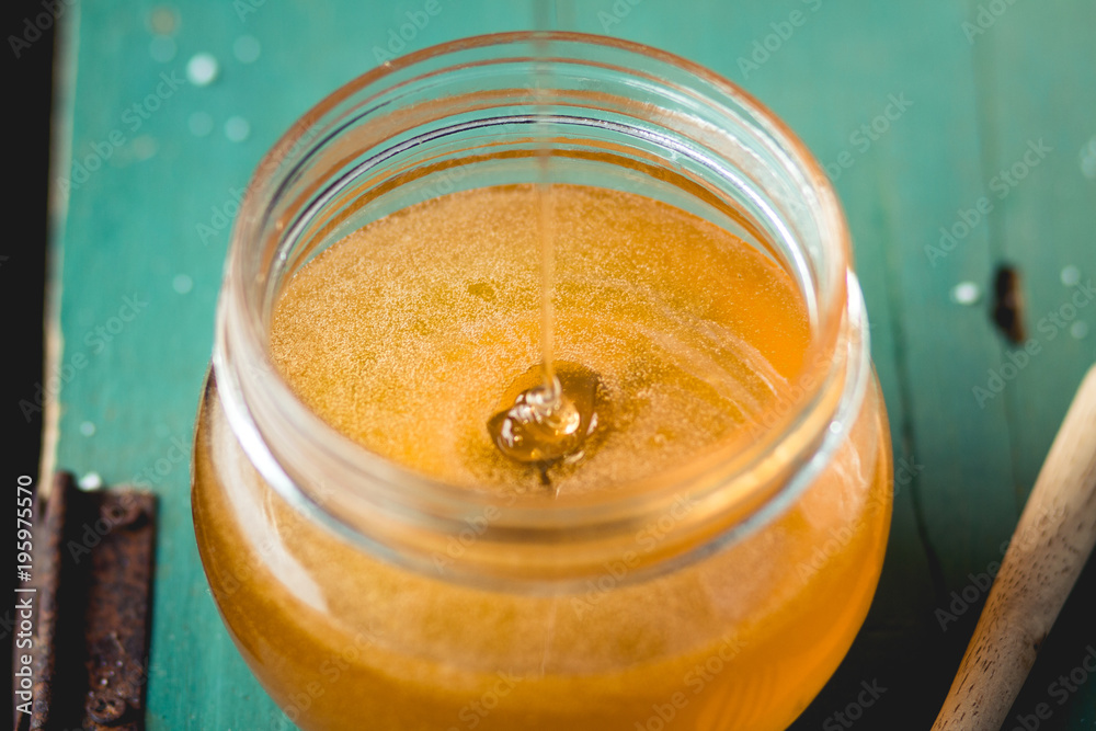 Honey in a glass bottle On blue wood in low light Honey in a glass bottle On blue wood in low light