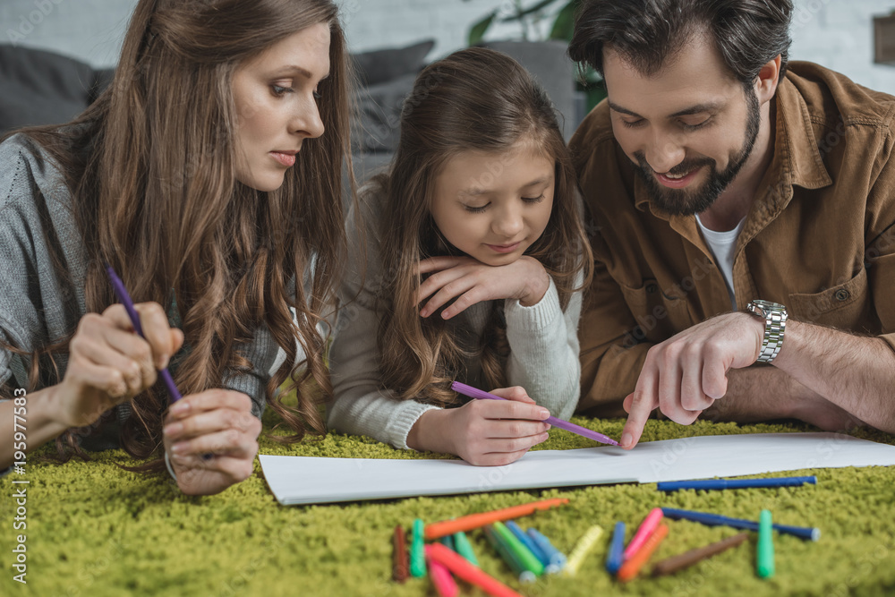 Fototapeta premium happy father pointing on something in album to daughter