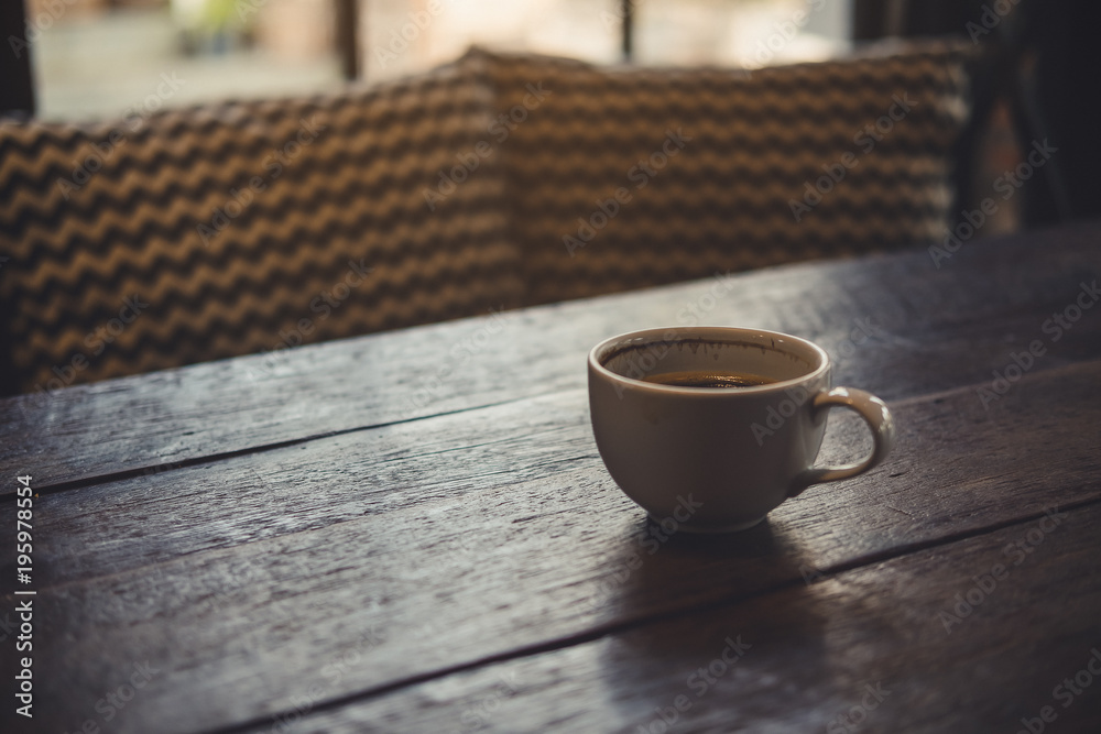 Fototapeta premium Closeup image of hot coffee cup on vintage wooden table in cafe