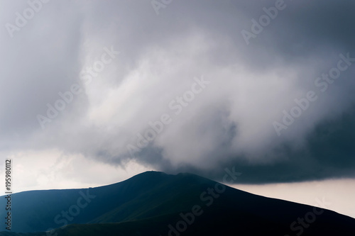 Storm rainy clouds above mountains. Apocalypse fantasy fabulous sky. Beautiful windy dramatic cloudscape at nature. Picturesque scenic view outdoor. Travel in wild territory. Discover rocky hills. © benevolente