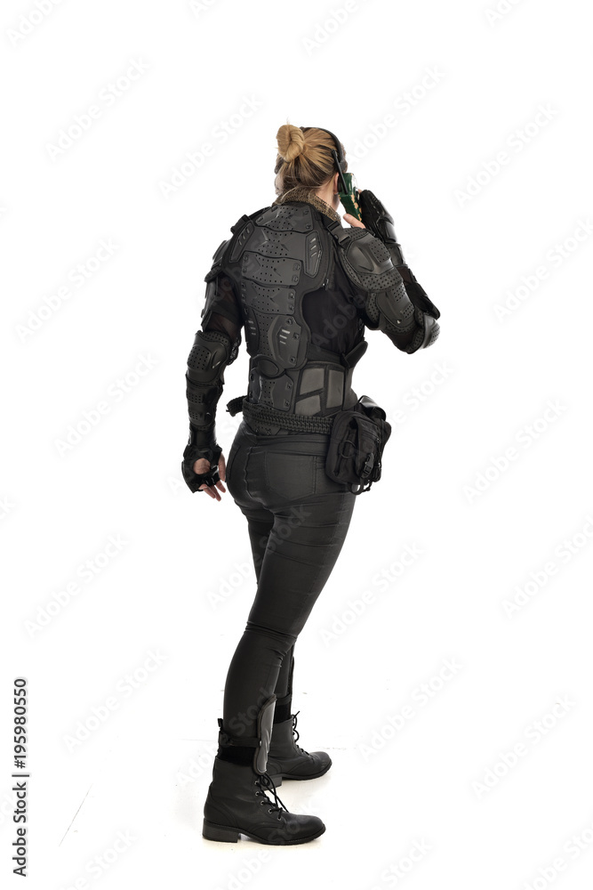 full length portrait of female soldier wearing black tactical armour, standing pose holding a walkie talkie, isolated on white studio background. full length portrait of female soldier wearing black tactical armour, standing pose holding a walkie talkie, isolated on white studio background.