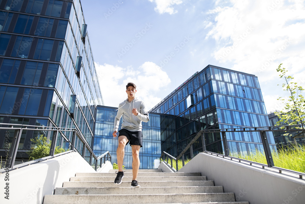 Young athlete running in front of glass buildings.