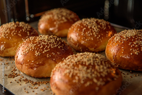 homemade burger rolls sprinkled with sesame seeds are baked in the oven photo