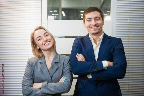 Wallpaper Mural Two respectable business people in formal suits stand together. Man and woman at office room pose to camera. Teamwork, cooperation, success concept Torontodigital.ca