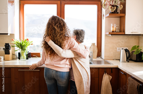 A teenage girl with grandmother at home, hugging.